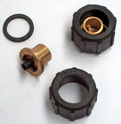 Daikin Anschlusskomponenten bestehend aus einem schwarzen Kunststoffteil, einem goldenem Metallteil und einem O-Ring. Teile für eine Verbindung oder Montage.